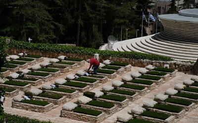 Chaim Frenkel puts a flower and a note on a grave on Mount Herzl in Jerusalem ahead of next week's Memorial Day, on April 23, 2020. (Judah Ari Gross/Times of Israel)