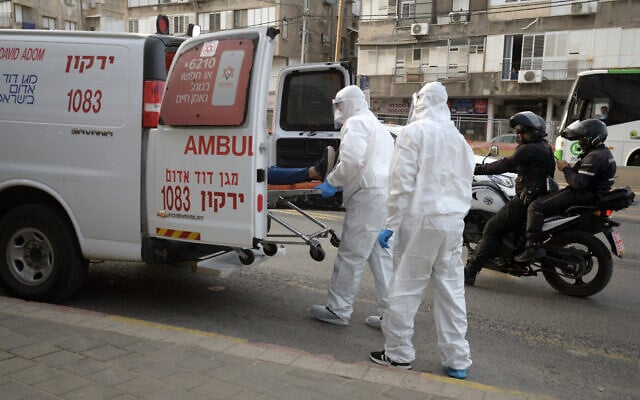 Illustrative. Magen David Adom paramedics transferring a man suspected of carrying coronavirus to an ambulance in the Tel Aviv suburb of Bnei Brak, March 31, 2020. (Gili Yaari/ Flash90) Illustrative. Magen David Adom paramedics transferring a man suspected of carrying coronavirus to an ambulance in the Tel Aviv suburb of Bnei Brak, March 31, 2020. (Gili Yaari/ Flash90)