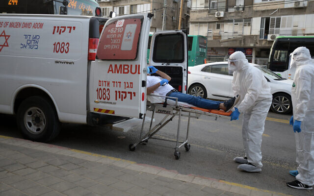 Magen David Adom paramedics in protective gear put a man suspected of having the coronavirus into an ambulance in the the Tel Aviv suburb of Bnei Brak, March 31, 2020. (Gili Yaari/Flash90) Magen David Adom paramedics in protective gear put a man suspected of having the coronavirus into an ambulance in the the Tel Aviv suburb of Bnei Brak, March 31, 2020. (Gili Yaari/Flash90)