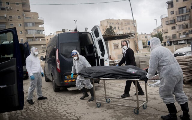 Workers wearing protective clothes carry the body of a patient who died from complications of coronavirus, at the Shamgar Funeral Home in Jerusalem on April 1, 2020 (Yonatan Sindel/Flash90) Workers wearing protective clothes carry the body of a patient who died from complications of coronavirus, at the Shamgar Funeral Home in Jerusalem on April 1, 2020 (Yonatan Sindel/Flash90)