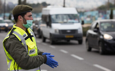 An IDF soldier at a temporary checkpoint in Jerusalem to check that Israelis are not violating restrictions meant to contain the coronavirus, April 2, 2020. (Nati Shohat//Flash90)