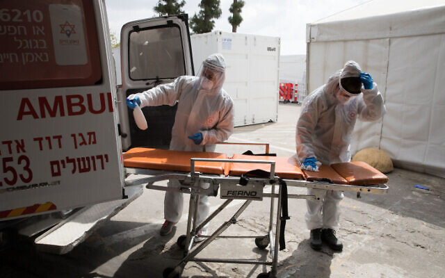 Magen David Adom workers cleaning an ambulance in Jerusalem on April 2, 2020. (Nati Shohat/Flash90) Magen David Adom workers cleaning an ambulance in Jerusalem on April 2, 2020. (Nati Shohat/Flash90)