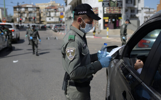 An Israeli border policeman inspects the papers of a driver at a checkpoint located at the exit of the ultra-Orthodox city of Bnei Brak, April 3, 2020. (Gili Yaari /Flash90) An Israeli border policeman inspects the papers of a driver at a checkpoint located at the exit of the ultra-Orthodox city of Bnei Brak, April 3, 2020. (Gili Yaari /Flash90)