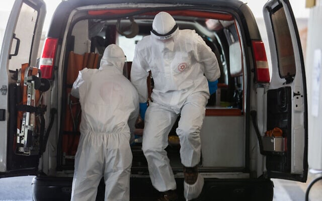 Magen David Adom workers wearing protective clothing, as a preventive measure against the coronavirus evacuate a suspected coronavirus patient to the new coronavirus unit at Shaare Zedek Medical Center, in Jerusalem on April 3, 2020. (Nati Shohat/Flash90) Magen David Adom workers wearing protective clothing, as a preventive measure against the coronavirus evacuate a suspected coronavirus patient to the new coronavirus unit at Shaare Zedek Medical Center, in Jerusalem on April 3, 2020. (Nati Shohat/Flash90)