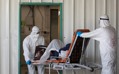 Magen David Adom workers wearing protective clothing as a preventive measure against the coronavirus evacuate a patient with suspected coronavirus outside a coronavirus unit at Shaare Zedek hospital in Jerusalem on April 3, 2020. ( Nati Shohat/Flash90)