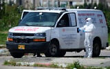Israeli Magen David Adom personel and soldiers at a drop off station for residents from Bnei Brak who have been infected by the Coronavirus, and on their way to quarantine hotels, near the Ayalon mall on April 3, 2020. (Tomer Neuberg/ Flash90)