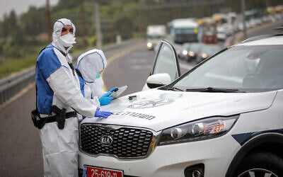 Police officers in protective gear stand on Route 1 near Jerusalem on April 5, 2020, after a man infected with the coronavirus was arrested on a bus traveling to the city. (Flash90)