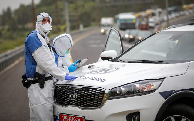 Police officers in protective gear stand on Route 1 near Jerusalem on April 5, 2020, after a man infected with the coronavirus was arrested on a bus traveling to the city. (Flash90) Police officers in protective gear stand on Route 1 near Jerusalem on April 5, 2020, after a man infected with the coronavirus was arrested on a bus traveling to the city. (Flash90)