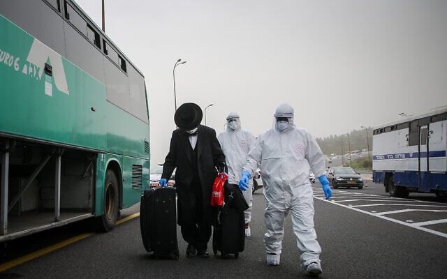 Medics wearing protective clothes walk near a bus with a man who was tested positive for the coronavirus on Route 1 near Jerusalem on April 5, 2020. (Flash90) Medics wearing protective clothes walk near a bus with a man who was tested positive for the coronavirus on Route 1 near Jerusalem on April 5, 2020. (Flash90)