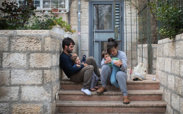 An Israeli family sits on the steps outside their apartment building in Jerusalem, as they stay at home with their children during a nation-wide quarantine, on March 31, 2020. (Hadas Parush/Flash90) An Israeli family sits on the steps outside their apartment building in Jerusalem, as they stay at home with their children during a nation-wide quarantine, on March 31, 2020. (Hadas Parush/Flash90)