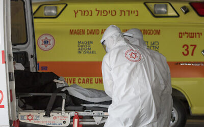 Illustrative: Magen David Adom medics wearing protective clothing, as a preventive measure against the coronavirus transfer a patient to the new coronavirus unit at Shaare Zedek hospital in Jerusalem on April 6, 2020. (Nati Shohat/Flash90)