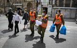 Illustrative: Israeli soldiers of the Home Front Command give out food packages to elderly people obliged to stay home due coronavirus ahead of the Passover holiday, in Jerusalem. April 7, 2020. (Olivier Fitoussi/ Flash90)