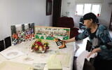 Perahia Shilo arranges the Passover Seder dinner table next to a picture of her children and grandchildren, on the eve of the Jewish holiday of Passover, in the West Bank settlement of Efrat, April 8, 2020. (Gershon Elinson/Flash90)