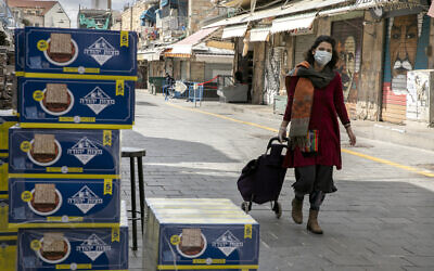 A woman walks past boxes of matza for sale at the Mahane Yehuda market in Jerusalem on April 8, 2020. (Olivier Fitoussi/Flash90)