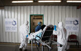 Magen David Adom workers wearing protective clothing with a patient with suspected coronavirus at Shaare Zedek hospital in Jerusalem on April 10, 2020 (Nati Shohat/Flash90)