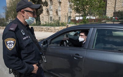 An Israel Police officer at a temporary checkpoint at the entrance to Neve Yaakov, Jerusalem, April 12, 2020, (Nati Shohat/Flash90)