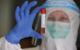 A Clalit medical team member wearing protective gear, with a sample for a coronavirus test in Lod, April 12, 2020.
(Yossi Aloni/Flash90)