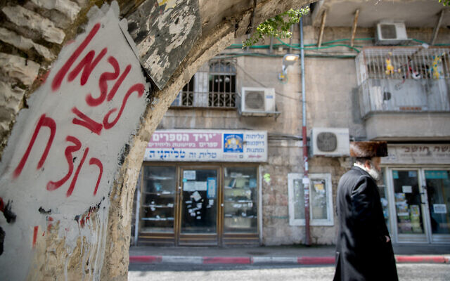 An ultra-Orthodox man walks past graffiti against Health Minister Yaakov Litzman in Jerusalem's Mea Shearim neighborhood on April 12, 2020. The graffiti reads "Litzman = murderer." (Yonatan Sindel/Flash90) An ultra-Orthodox man walks past graffiti against Health Minister Yaakov Litzman in Jerusalem's Mea Shearim neighborhood on April 12, 2020. The graffiti reads "Litzman = murderer." (Yonatan Sindel/Flash90)