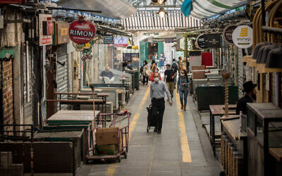 People walk through Jerusalem's mostly shuttered Mahane Yehuda Market on April 16, 2020. (Yonatan Sindel/Flash90)