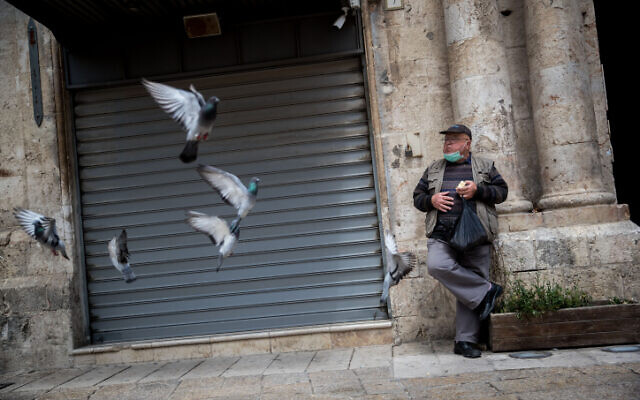 A man feeds pigeons at Jaffa Gate in the Old City of Jerusalem on April 17, 2020. (Yonatan Sindel/Flash90) A man feeds pigeons at Jaffa Gate in the Old City of Jerusalem on April 17, 2020. (Yonatan Sindel/Flash90)