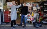 A worker checks the temperature of a customer at a store in the northern Arab Israeli town of Deir al-Asad on April 18, 2020. (Basel Awidat/Flash90)