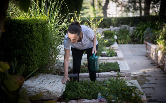 A woman cleans a grave of a family member at the military cemetery on Mount Herzl in Jerusalem on April 22, 2020. This year, due to the outbreak of the Coronavirus, there will be restrictions on going to the cemeteries on Memorial Day itself. (Yonatan Sindel/Flash90) A woman cleans a grave of a family member at the military cemetery on Mount Herzl in Jerusalem on April 22, 2020. This year, due to the outbreak of the Coronavirus, there will be restrictions on going to the cemeteries on Memorial Day itself. (Yonatan Sindel/Flash90)