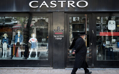 An ultra-Orthodox Jewish man walks past a closed shop of the 'Castro' fashion chain in downtown Jerusalem on April 26, 2020. (Yonatan Sindel/Flash90)