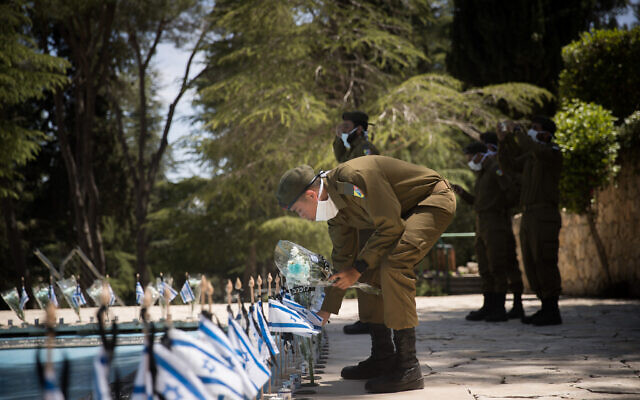 Israeli soldiers place flowers on and salute the graves of fallen Israeli soldiers at the Mount Herzl military cemetery on April 27, 2020, as the cemetery will be closed to visitors for Memorial Day due to the coronavirus pandemic. (Yonatan Sindel/Flash90) Israeli soldiers place flowers on and salute the graves of fallen Israeli soldiers at the Mount Herzl military cemetery on April 27, 2020, as the cemetery will be closed to visitors for Memorial Day due to the coronavirus pandemic. (Yonatan Sindel/Flash90)