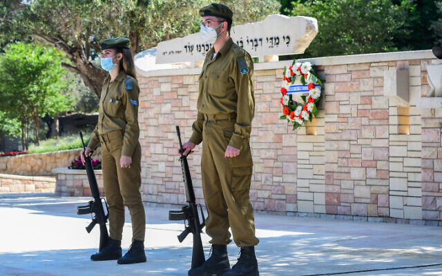 Soldiers stand near the graves of fallen troops at the Kiryat Shaul Military Cemetery in Jerusalem, as Israel marks Memorial Day for the fallen soldiers and victims of terror on April 28, 2020 (Avshalom Sassoni/Flash90)