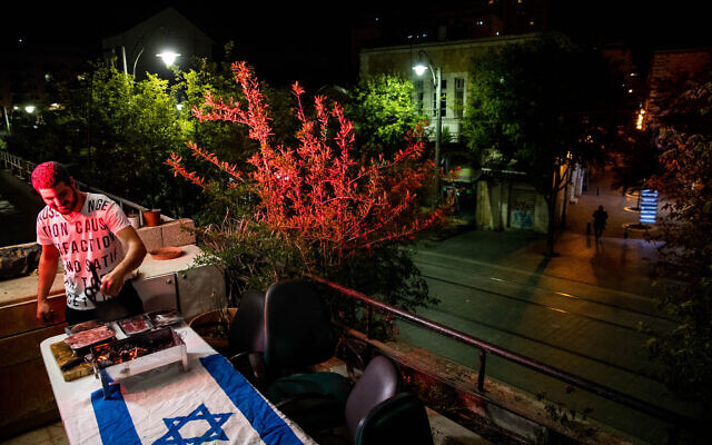 An Israeli cooking meat on a barbecue at his home on Jaffa Road in Jerusalem, as Israel celebrates its 72th Independence Day under lockdown, April 28, 2020.  (Yonatan Sindel/Flash90)