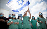 Medical staff cheer an Israeli air force aerobatic team flying over Ichilov hospital in Tel Aviv on Israel's 72nd Independence Day, April 29, 2020. (Miriam Alster/Flash90)
