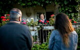 A son accompanied by his daughter stand 2 meters away from his mother's balcony as he meets with her in Jerusalem during the coronavirus pandemic, on April 30, 2020. (Olivier Fitoussi/Flash90)