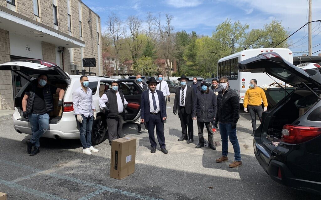 Rabbi Eitan Rubin, center, poses with volunteers including students and professionals as they load up personal protective equipment in the parking lot of Beit Midrash of Great Neck. (Cathryn J. Prince/ Times of Israel)