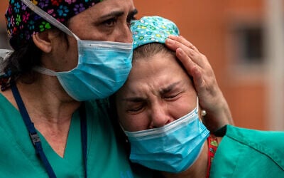 Health workers cry during a memorial for their co-worker that died of the coronavirus at the Severo Ochoa Hospital in Leganes in Leganes, Spain, April 10, 2020. (AP/Manu Fernandez)