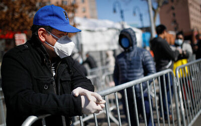 A patient wears a protective mask and gloves while waiting for COVID-19 testing outside Elmhurst Hospital Center, in New York, March 27, 2020. (AP/John Minchillo)