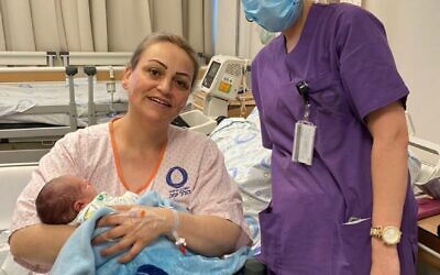 After seven years of fertility treatment and a 48-hour labor,  Danit Shipe holds her baby, born on Israel's 72nd Independence Day, April 29, 2020. Midwife Katia Amarna stands next to her. (Hillel Yaffe Medical Center)