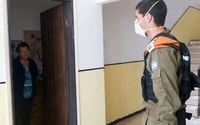 An IDF soldier visits an elderly Israeli woman as part of a military effort to assist the country's at-risk population during the coronavirus outbreak on April 2, 2020. (Israel Defense Forces)