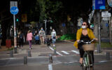 People wear protective masks in Tel Aviv, on April 18, 2020 (Miriam Alster/FLASH90)
