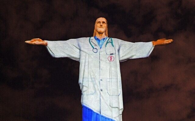 View of the world famous Christ the Redeemer statue on Easter day with a doctor's uniform projected on it in honor of all the medical staff fighting the COVID-19 pandemic worldwide in Rio de Janeiro, Brazil on April 12, 2020. (Photo by CARL DE SOUZA / AFP) View of the world famous Christ the Redeemer statue on Easter day with a doctor's uniform projected on it in honor of all the medical staff fighting the COVID-19 pandemic worldwide in Rio de Janeiro, Brazil on April 12, 2020. (Photo by CARL DE SOUZA / AFP)
