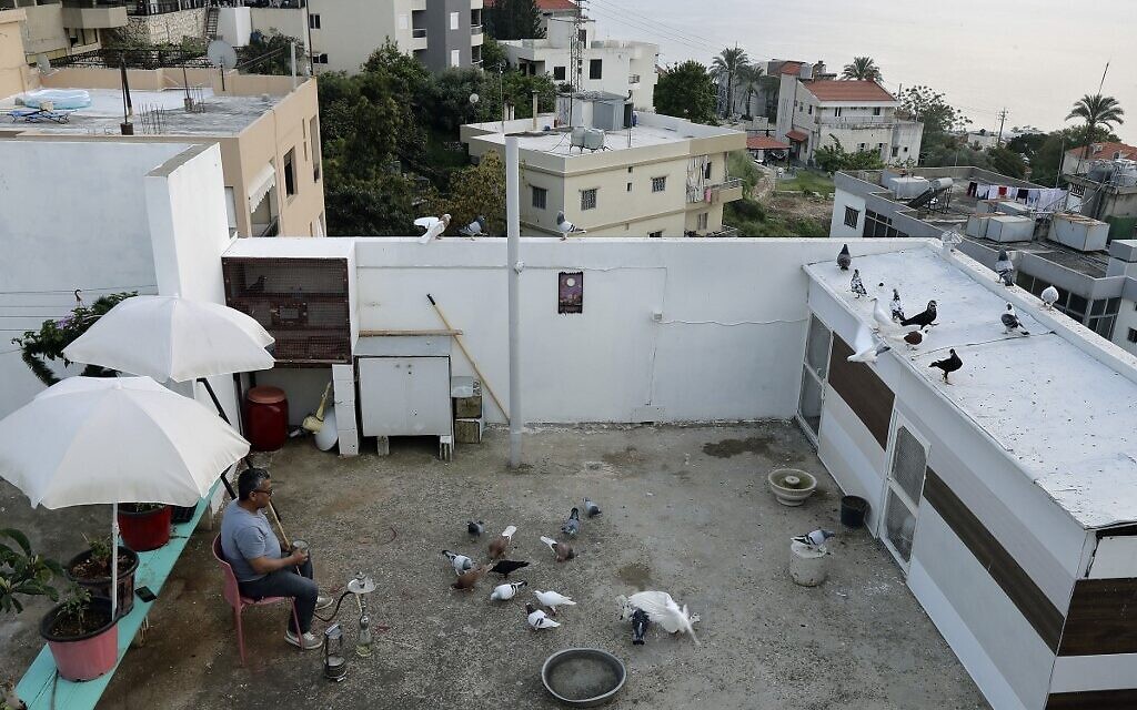 Syrian national Salah Sido Rcho smokes a waterpipe as he observes his pigeons on the rooftop of his building, during a lockdown imposed by the authorities in a bid to stem the spread of the novel coronavirus in the town of Halat, north of the capital Beirut on April 21, 2020. (Photo by JOSEPH EID / AFP)