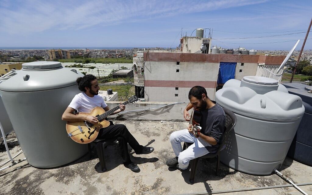 Lebanese Musician Ziad al-Zayyat (L) and his flatmate, interior designer Saad Molaeb, play their guitars on the rooftop of their building, during a lockdown imposed by the autorities in a bid to stem the spread of the novel coronavirus in the town of Hadath , north of the capital Beirut on May 4, 2020. (Photo by JOSEPH EID / AFP)