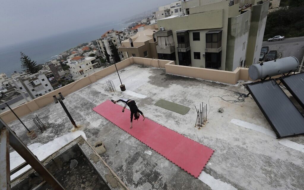 Lebanese gymnast Karen Dib practices on the rooftop of her building, during a lockdown imposed by the authorities in a bid to stem the spread of the novel coronavirus in the town of Halat, north of the capital Beirut on April 24, 2020.(Photo by JOSEPH EID / AFP)