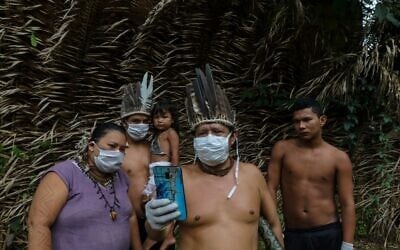 Satere-mawe indigenous people are seen using a smartphone to contact a doctor in Sao Paulo state to receive medical guidance amid the COVID-19 pandemic at the Sahu-Ape community, 80km from Manaus, Amazonas State, Brazil, on May 5, 2020. (Photo by RICARDO OLIVEIRA / AFP)