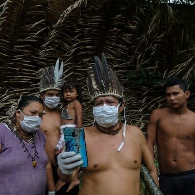 Satere-mawe indigenous people are seen using a smartphone to contact a doctor in Sao Paulo state to receive medical guidance amid the COVID-19 pandemic at the Sahu-Ape community, 80km from Manaus, Amazonas State, Brazil, on May 5, 2020. (Photo by RICARDO OLIVEIRA / AFP)