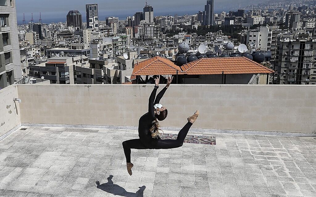 In this file photo taken on April 4, 2020 Sherazade Mami, a 28-year-old Tunisian professional dancer and performer at the Caracalla dance theater and a teacher at the Caracalla dance school, practices while wearing a surgical mask on the roof of her apartment building in the suburb of Dekwaneh on the eastern outskirts of Lebanon's capital Beirut on April 4, 2020. (Photo by JOSEPH EID / AFP)