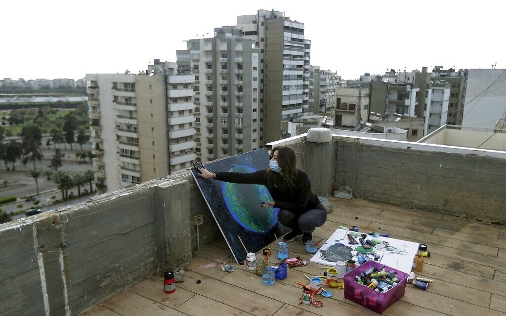 In this file photo taken on April 08, 2020, Lebanese Artist Hayat Nazer draws a painting on the roof of her family's apartment building in the northern coastal city of Tripoli, where she stays confined with her family due to the coronavirus (COVID-19) pandemic, on April 8, 2020. (Photo by Joseph EID / AFP)