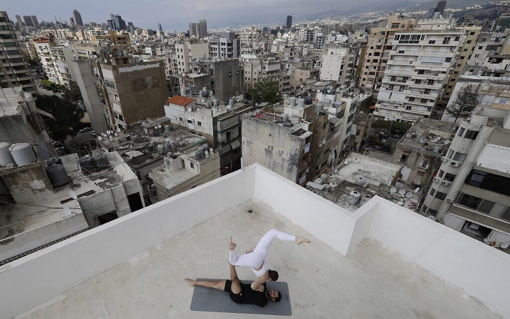In this file photo taken on April 27, 2020 Lebanese Yoga instructor Rabih el-Medawar, 29, practices Acroyoga with his Ukranian wife, fellow Yoga instructor and professional choreographer, Alona Aleksandrova, 24, on the roof of their apartment building in Beirut's Ain El-Remmaneh district on April 27, 2020 during the coronavirus (COVID-19) pandemic. (Photo by JOSEPH EID / AFP)