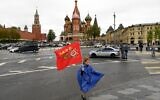 A girl with a red flag poses for a photo in downtown Moscow as she marks the 75th anniversary of the victory over Nazi Germany in World War II, May 9, 2020. (Kirill KUDRYAVTSEV / AFP)
