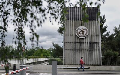 A woman wearing a protective facemask walks underneath a sign at the World Health Organization (WHO) headquarters in Geneva, Switzerland, May 12, 2020. (Fabrice Coffrini/AFP)
