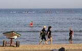 Beach-goers walk at a beach in the coastal city of Tel Aviv on May 20, 2020, as beaches open for the first time after two months of confinement due to the COVID-19 coronavirus pandemic. (Jack Guez/AFP)